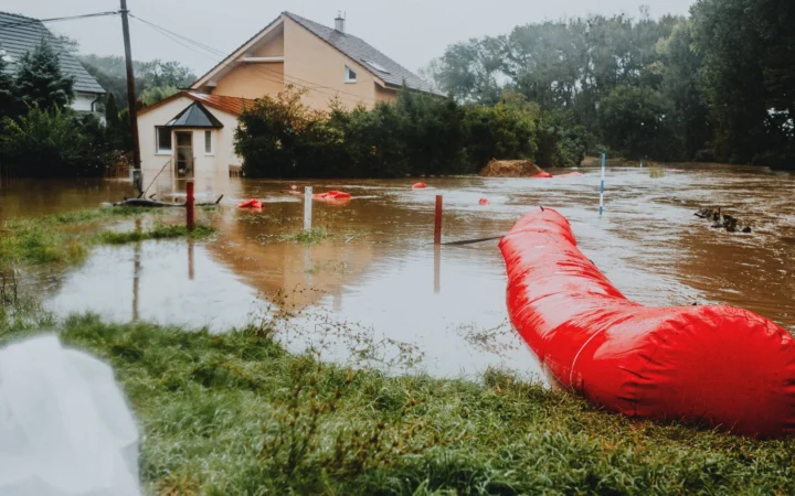 Flooded yard and home with a red flood barrier